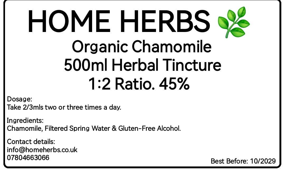 A product label card for Home Herbs Organic Chamomile 500ml Herbal Tincture. The white card features black text detailing the dosage, ingredients, contact information, and best before date, alongside a small green leaf graphic in the top right corner.