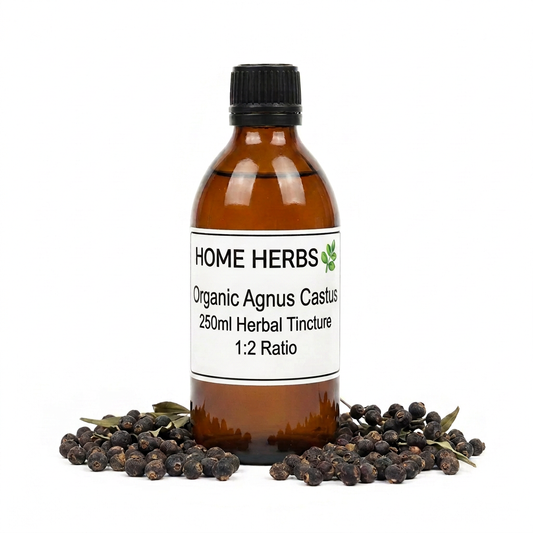 An amber glass bottle of Home Herbs Organic Agnus Castus 250ml Herbal Tincture with a black cap and white label, surrounded by black agnus castus berries and small green leaves on a white background.