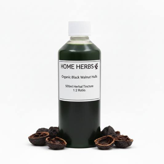 A 500ml bottle of Home Herbs Organic Black Walnut Hulls herbal tincture, filled with a very dark green liquid and topped with a white cap, displayed on a white background with whole and cracked black/green walnut shells arranged at its base.