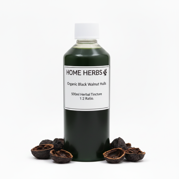 A 500ml bottle of Home Herbs Organic Black Walnut Hulls herbal tincture, filled with a very dark green liquid and topped with a white cap, displayed on a white background with whole and cracked black/green walnut shells arranged at its base.