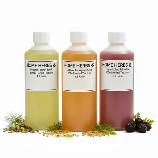 Three plastic bottles of Home Herbs herbal tinctures arranged side by side on a white background, with loose herbs and seeds placed around the base of each bottle. The bottles contain pale yellow, amber-orange, and mauve-pink liquids and are labeled Organic Fennel Seed, Organic Fennagreck Seed, and Organic Saw Palmetto.