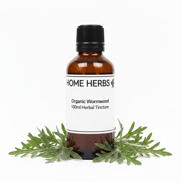 An amber glass bottle of Home Herbs Organic Wormwood 100ml Herbal Tincture with a white label and black cap, styled with fresh green wormwood leaves at the base on a white background.