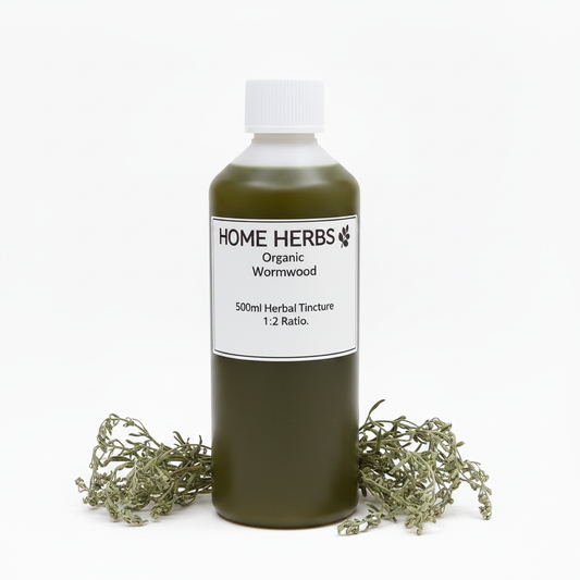 A 500ml bottle of Home Herbs Organic Wormwood herbal tincture, filled with an olive-green liquid and topped with a white cap, displayed on a white background with dried wormwood sprigs at its base.