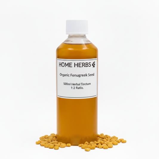 A 500ml clear plastic bottle filled with golden-brown organic fenugreek seed herbal tincture, topped with a white cap and labeled 'HOME HERBS Organic Fenugreek Seed'. Small yellow fenugreek pods are scattered around the base on a clean white background.